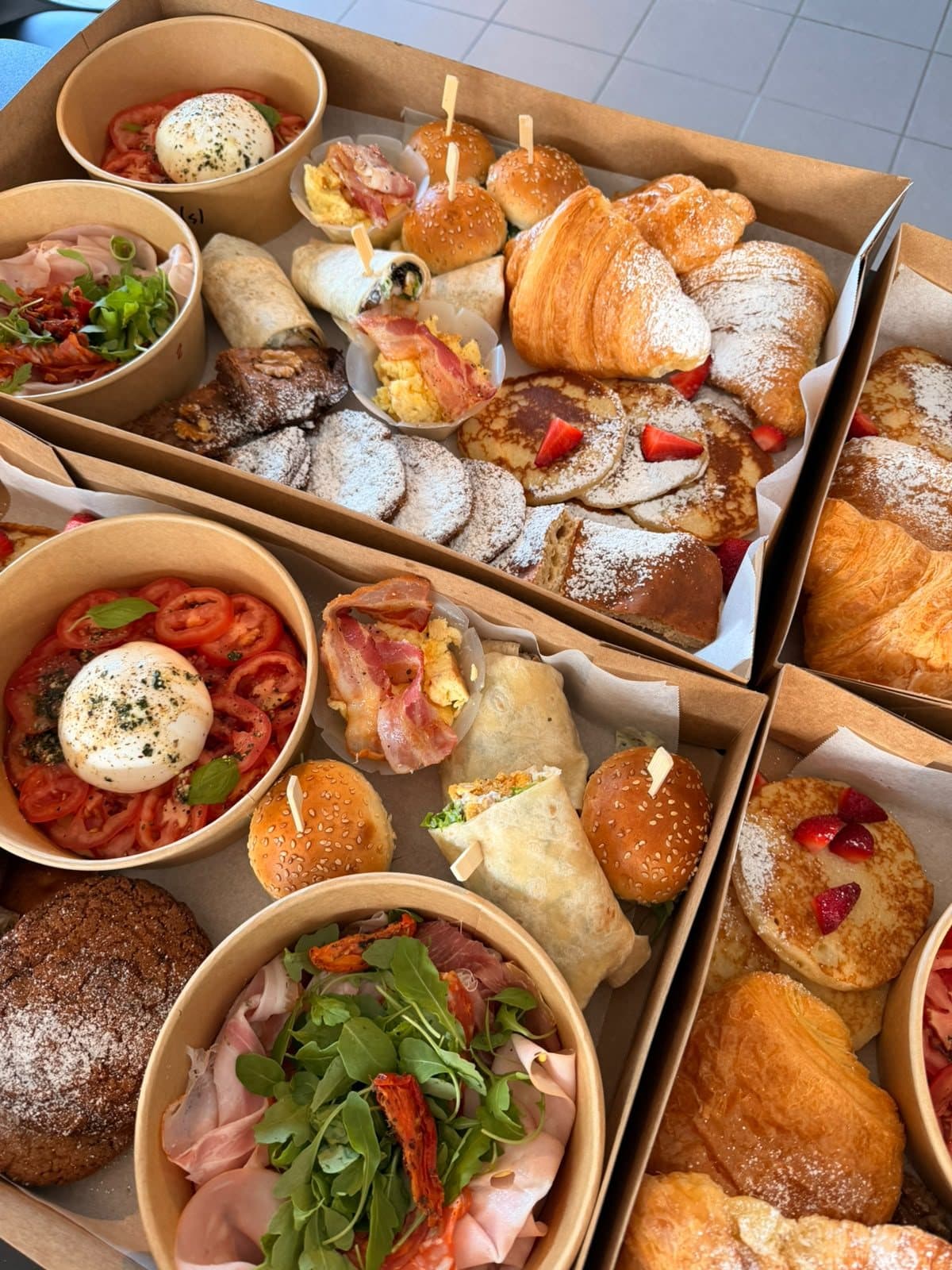 Une box garnie de croissants, de fruits et d'un bol de crudités.