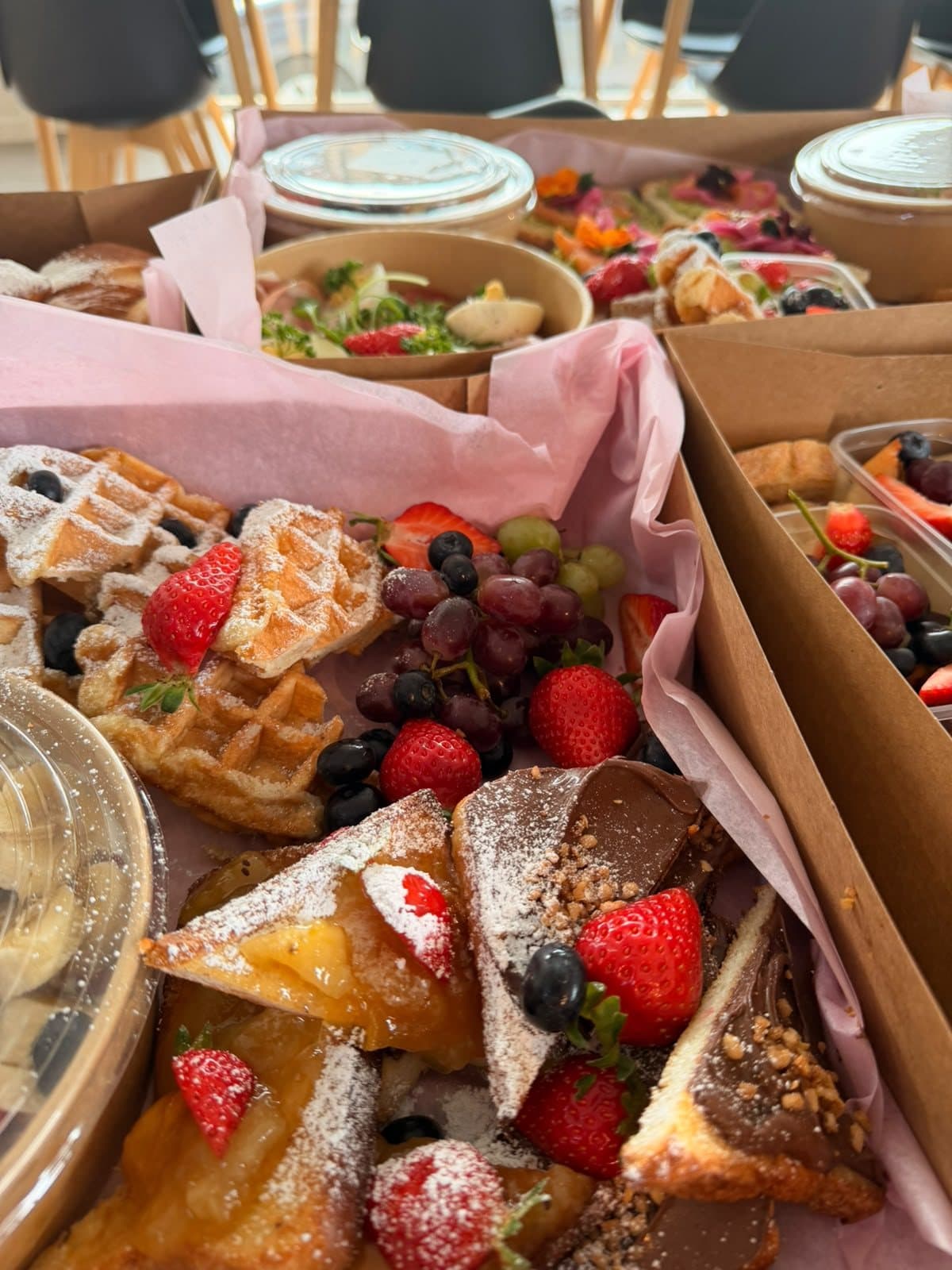 Une box de desserts avec des gaufres, des fraises et des pâtisseries.
