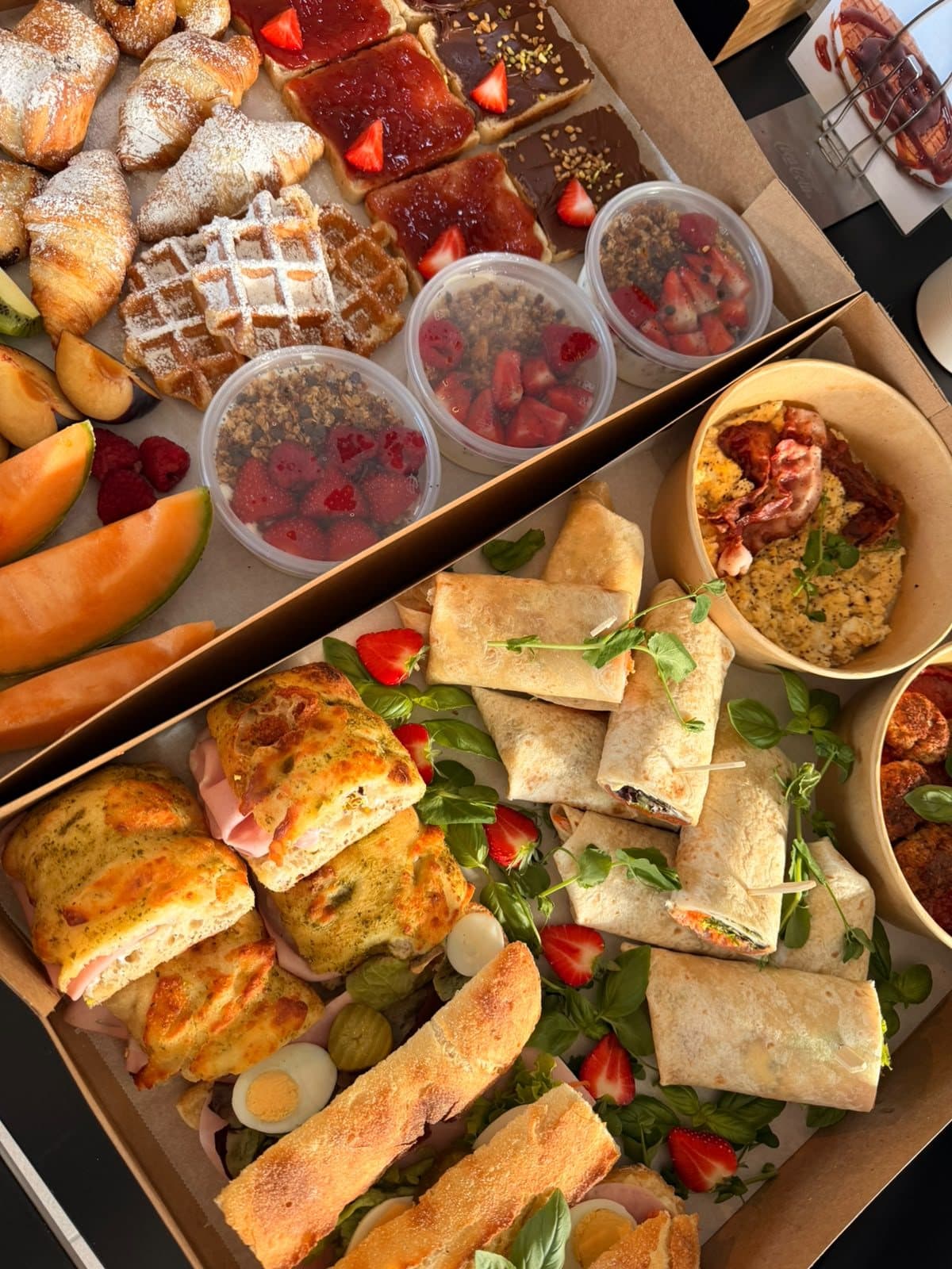 Un buffet de brunch avec des gaufres, des fraises, des quiches et des bouchées salées.
