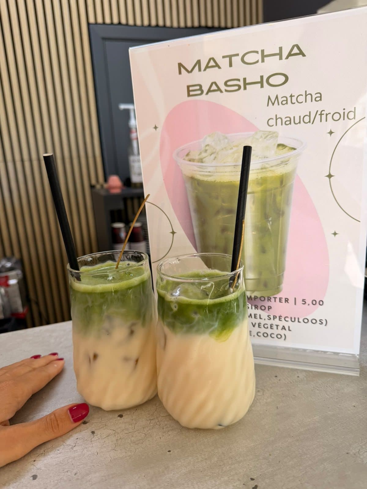 Deux matcha glacés servis dans des verres, devant l'affiche de Basho.