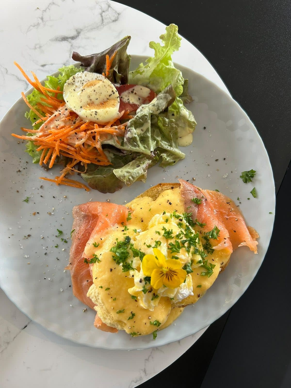 Une assiette d'œufs et de saumon fumé servie avec une salade de crudités.
