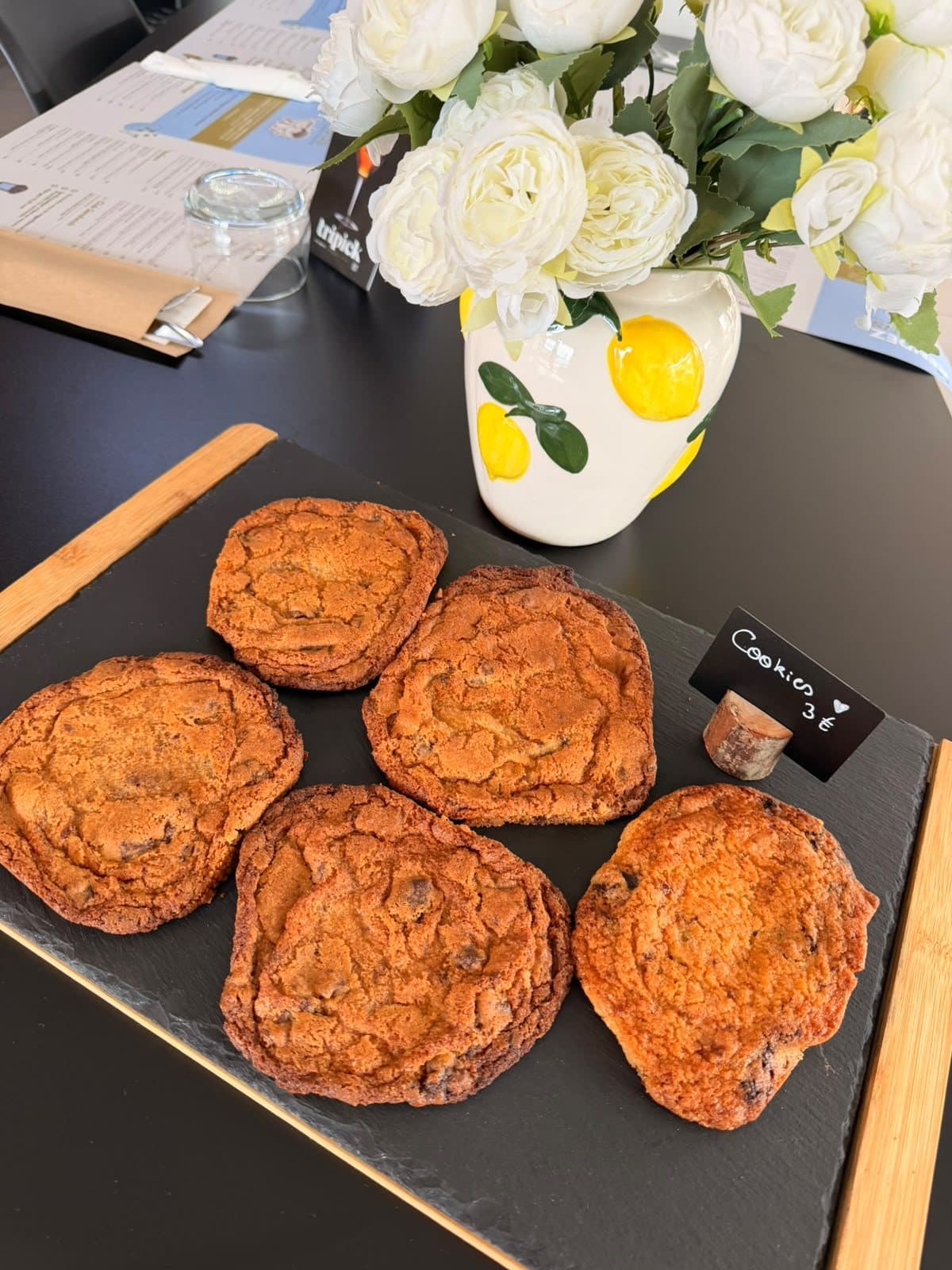 Des viennoiseries feuilletées sur un plateau, à côté d'un bouquet de fleurs blanches.