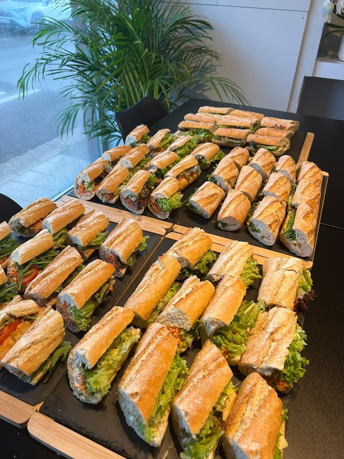 Plusieurs plateaux de mini-baguettes garnies, préparés pour une commande de groupe.