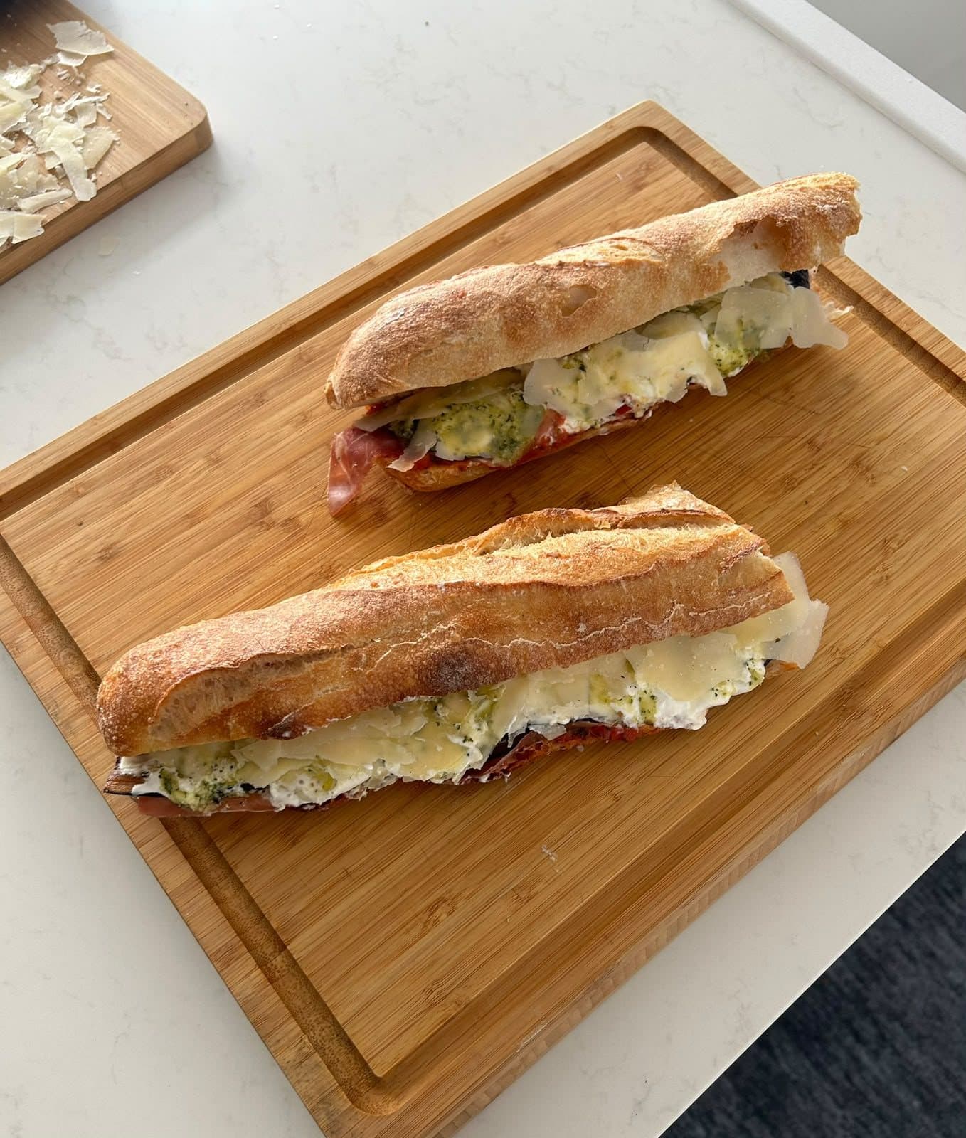 Un sandwich au pain frais, coupé en deux et garni, sur une planche en bois.