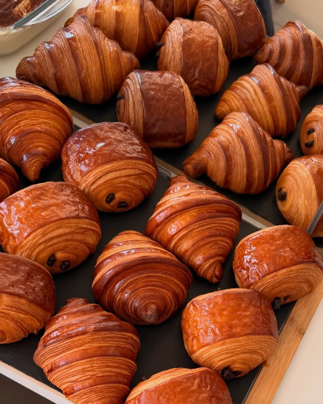 Des croissants tout juste sortis du four, rangés sur un plateau.